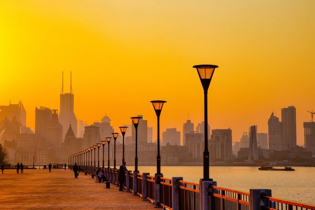 Huangpu River at sunset, with a bridge, street lamp, and buildings in the distance