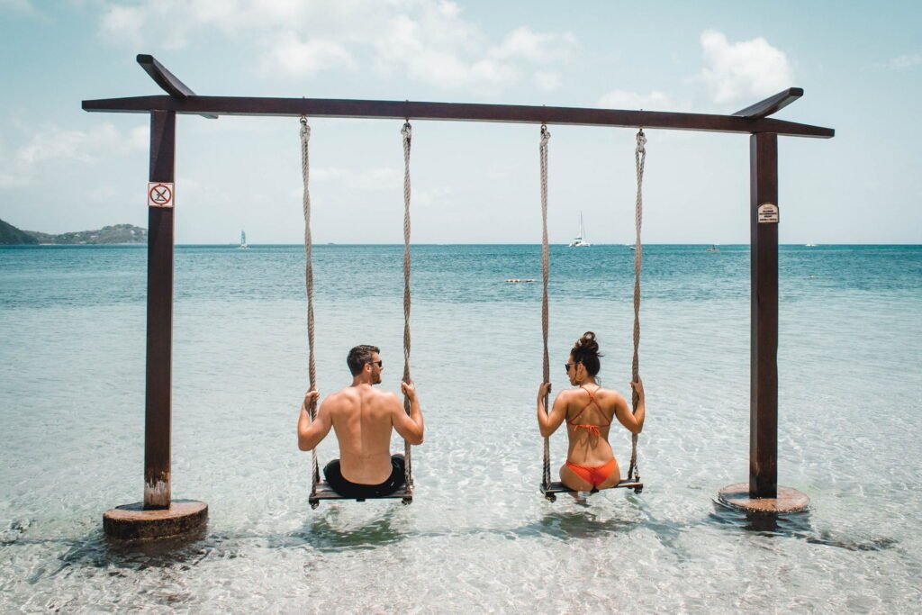 A couple sat on a swing in the shallows and looked at each other