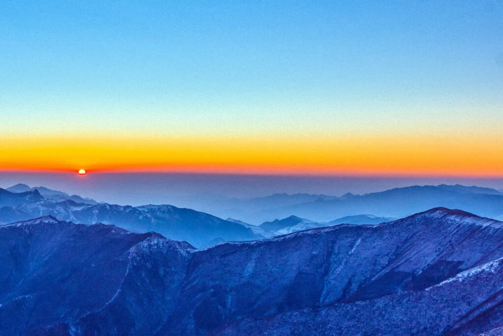 Serene Mount Wutai bathed in the gentle hues of a horizontal sunrise, enveloped in a mystical mist