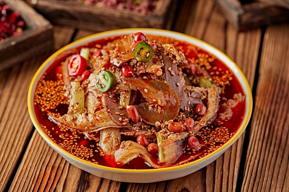 Pork Lungs in Chili Sauce drizzled with red oil, dotted with a few pieces of green and red peppers