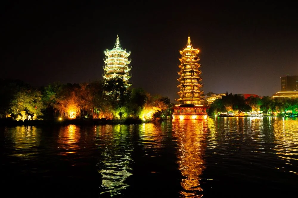 Night scene of the Two Rivers and Four Lakes, featuring the Sun and Moon Twin Towers with warm white and orange lighting