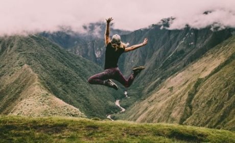 A woman jumps happily facing the valley